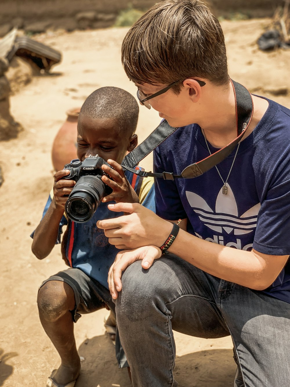 boy taking a knee and holding DSLR camera beside man taking a knee