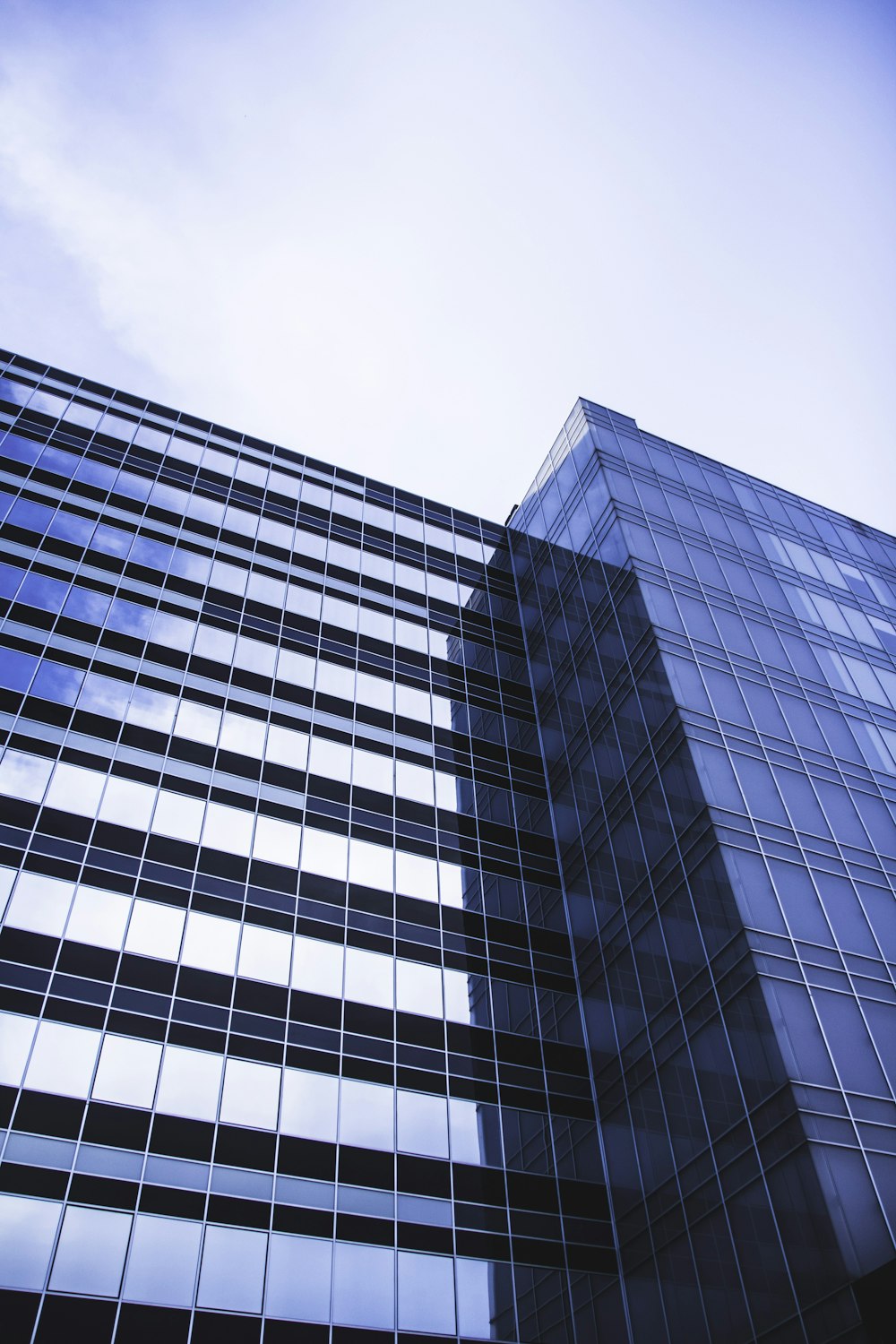 architectural photography of blue glass walled high-rise building under white and blue sky