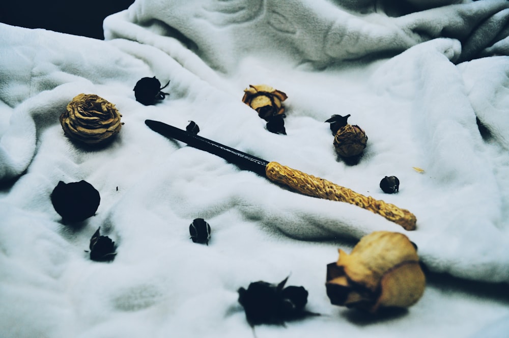 wand and dried rose flowers on white textile