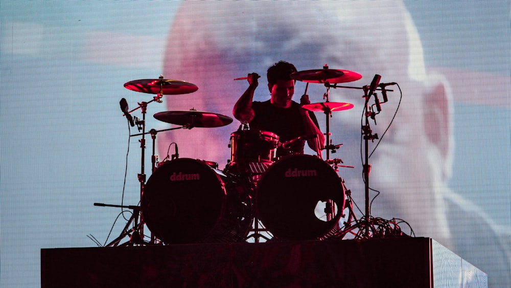 man wearing black crew-neck t-shirt playing drums