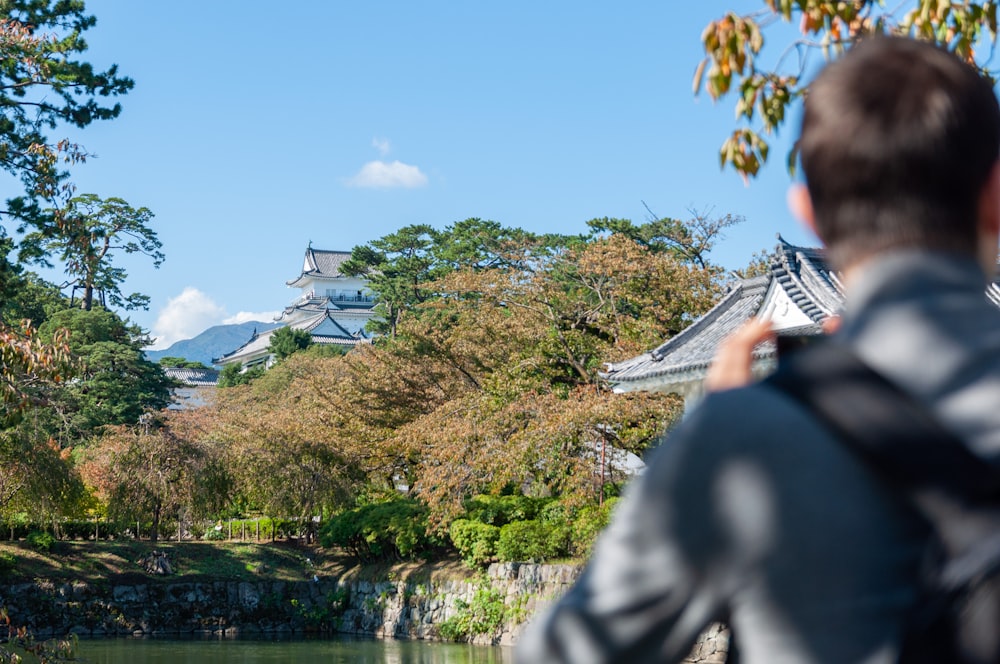 person standing near body of water beside temple under blue and white sky