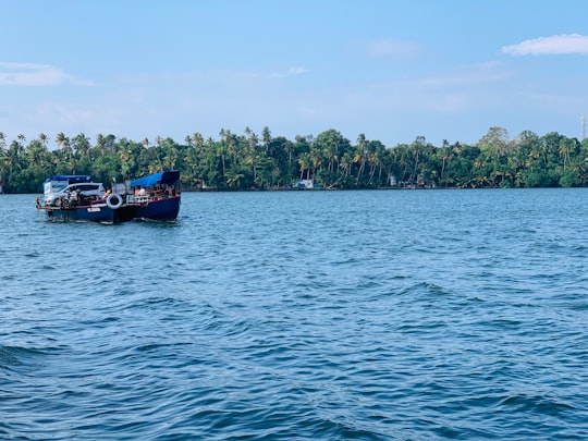 black and blue boat on blue body of water under blue and white sky in Munroe Island India