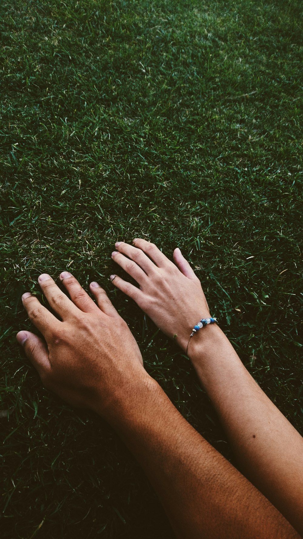 man and woman's hand on grass