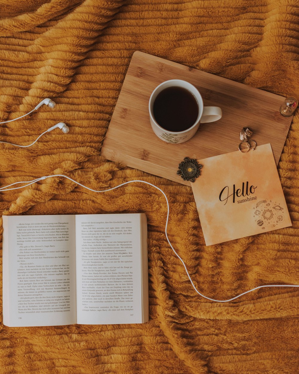 open book beside filled mug on brown wooden board