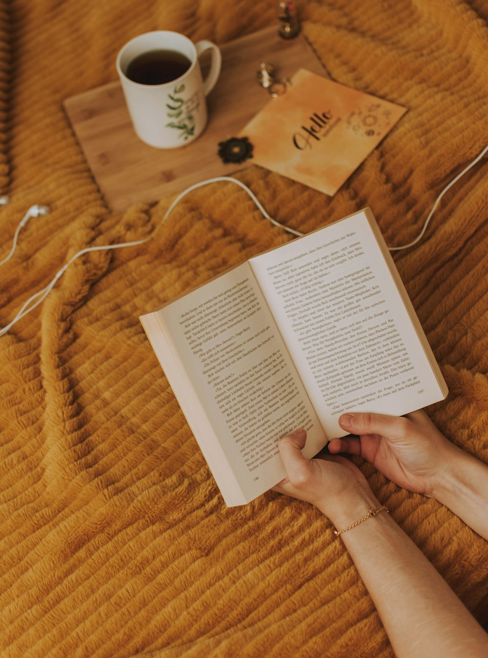 person reading book beside filled mug