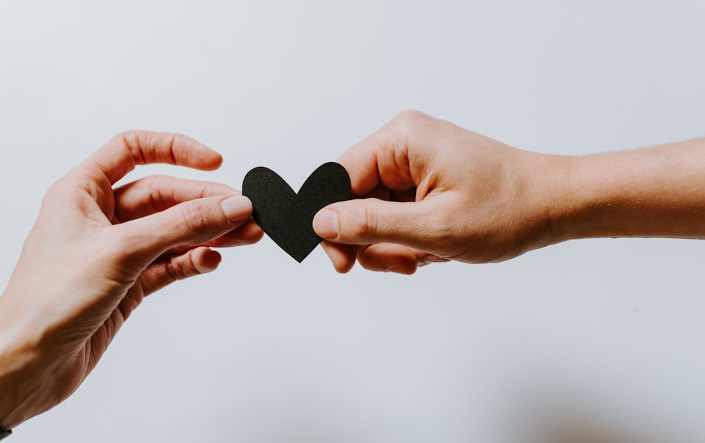 dos personas sosteniendo un corazón recortado de papel