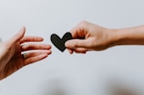 A close-up of hands holding a heart-shaped symbol representing care and support.