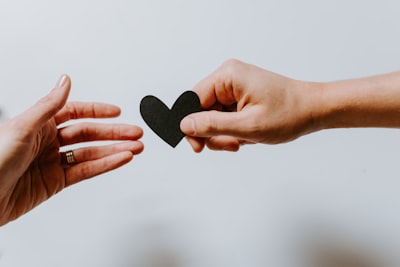 person reaching black heart cutout paper give zoom background