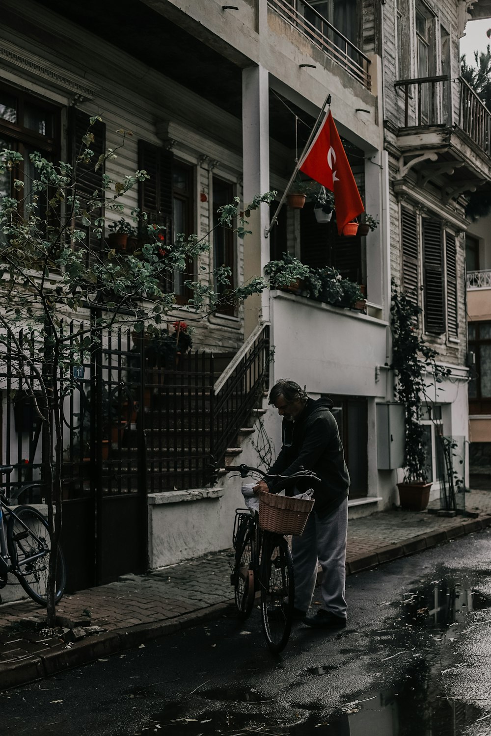 man wearing black jacket standing near brown bike beside building during daytime