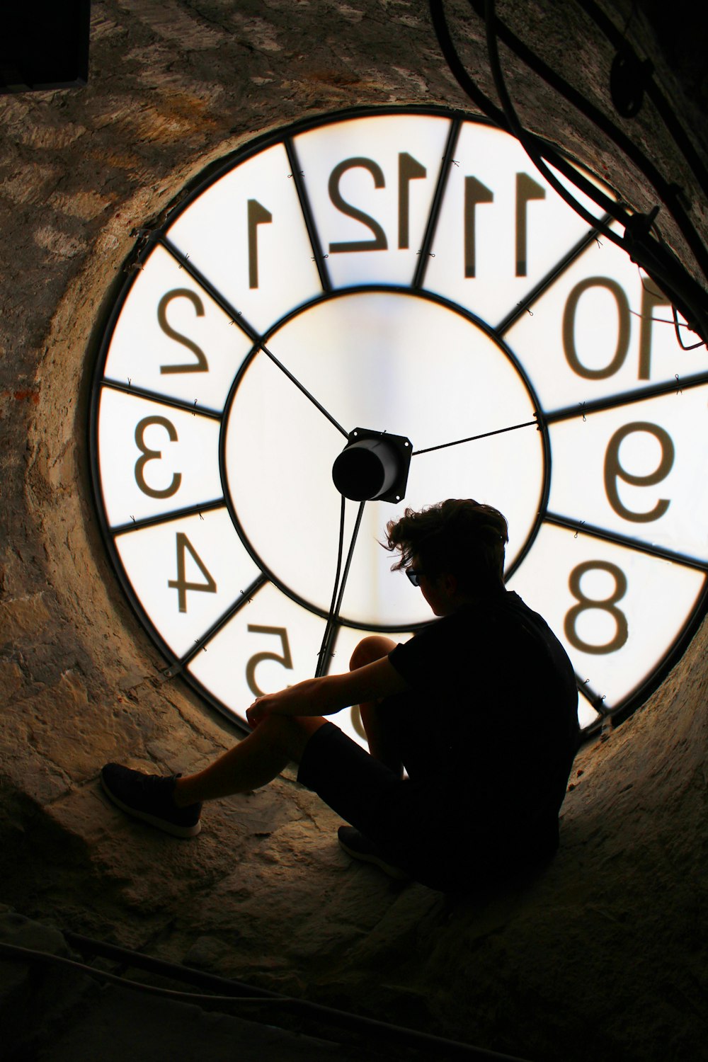 man sitting near big round analog clock