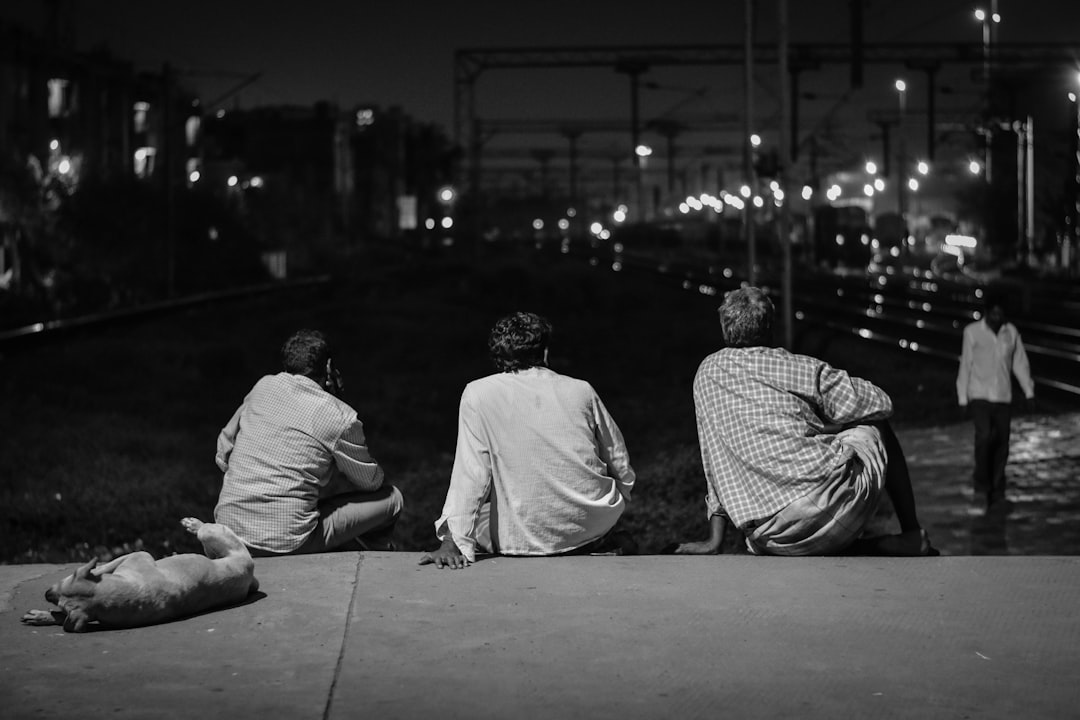 grayscale photography of three men sitting concrete floor
