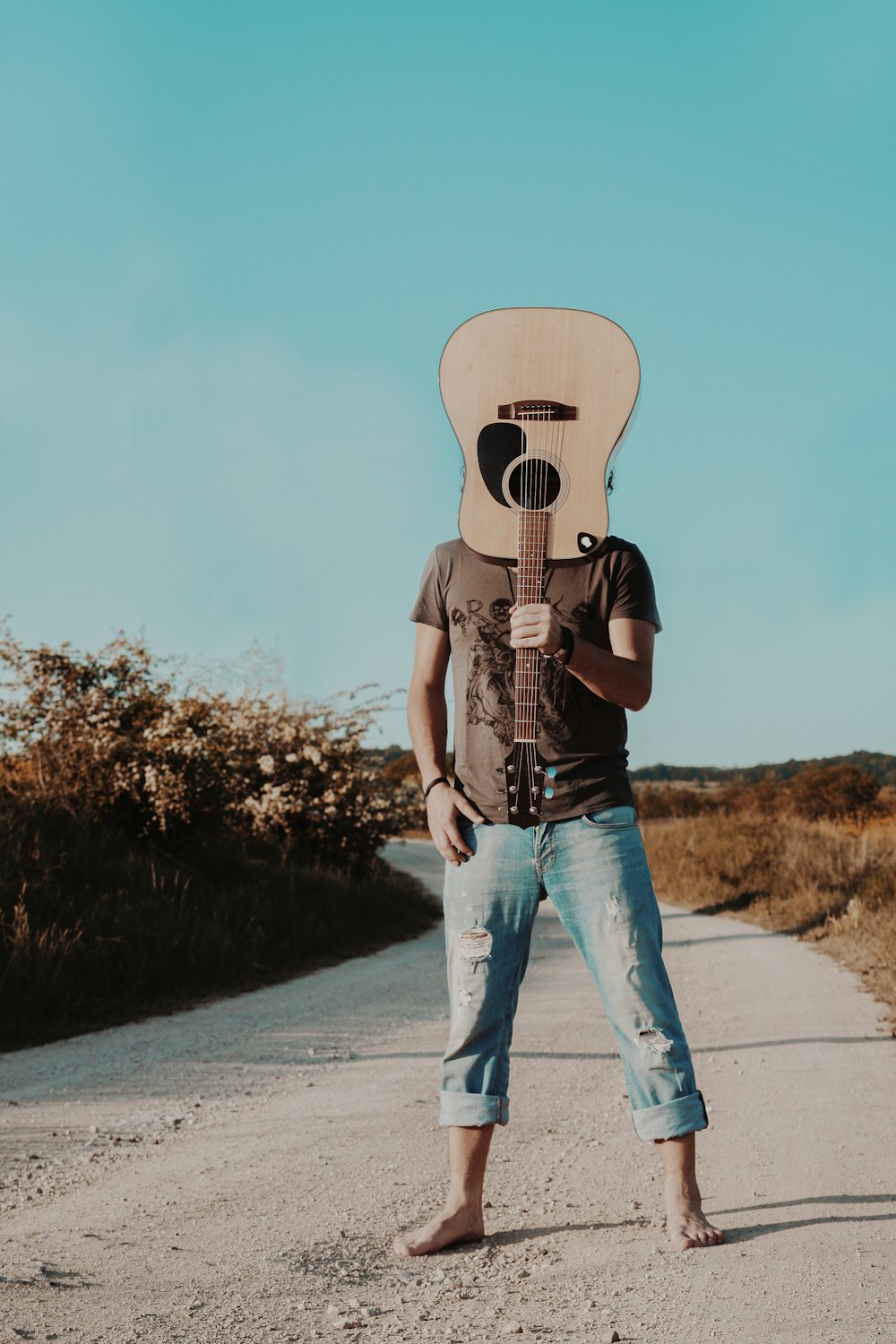 uomo che tiene la chitarra acustica marrone