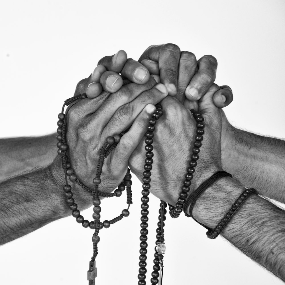 greyscale photograph of person holding prayer beads