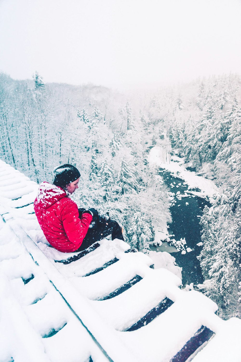 man wearing red jacket sitting on the snowy field