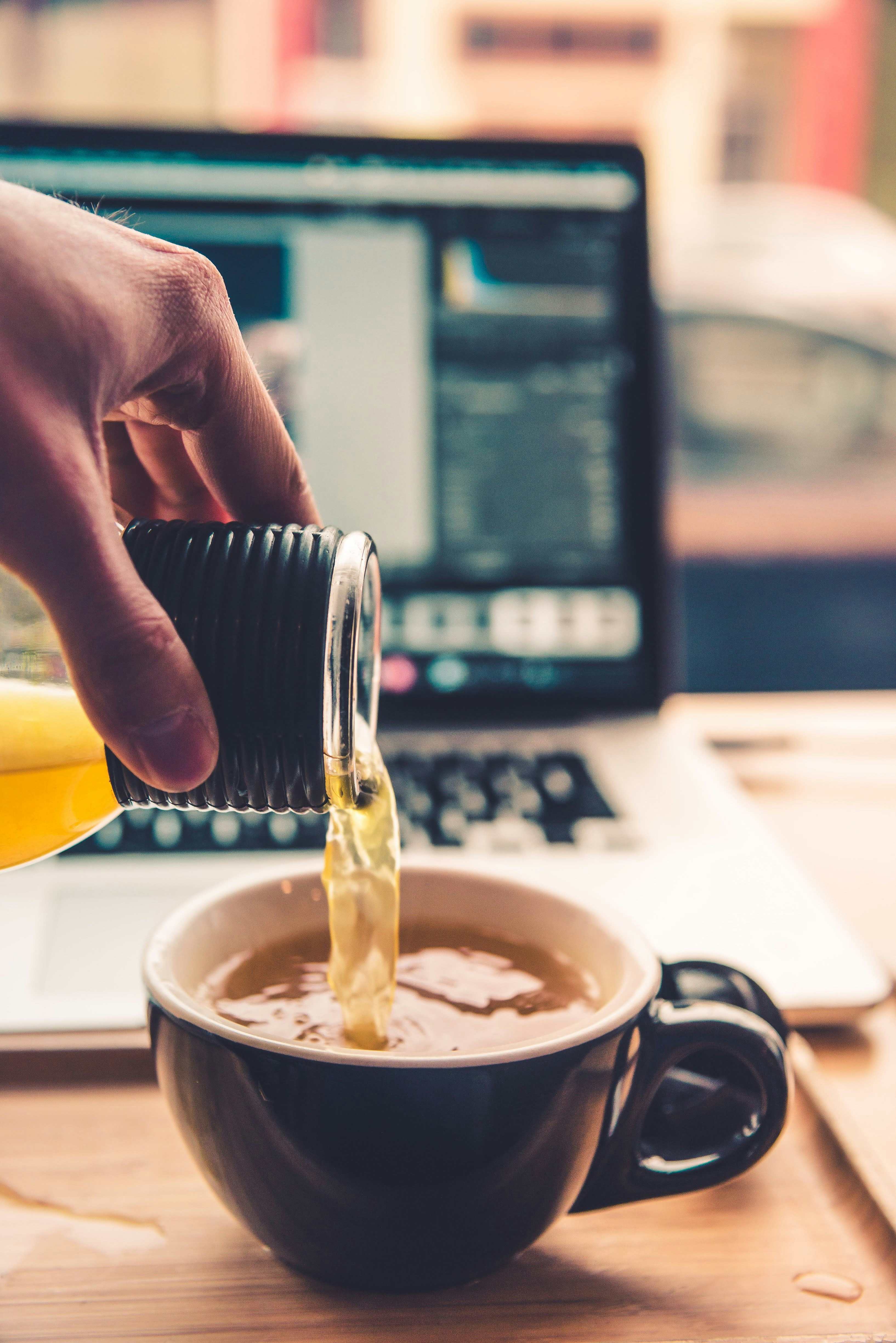 black ceramic teacup near the laptop