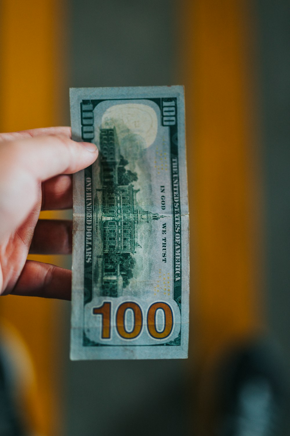 person holding 100 US Dollar banknote