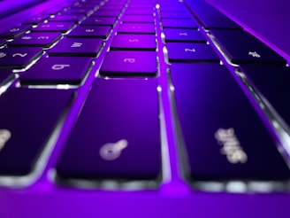 Close-up of hands typing rapidly on a futuristic keyboard with glowing violet keys.