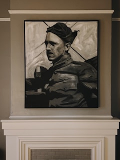 A black and white painting of a person wearing a cap, dressed in what appears to be military attire, is mounted on a wall above a fireplace. The artwork captures a somber expression, with strong shadows accentuating the features.