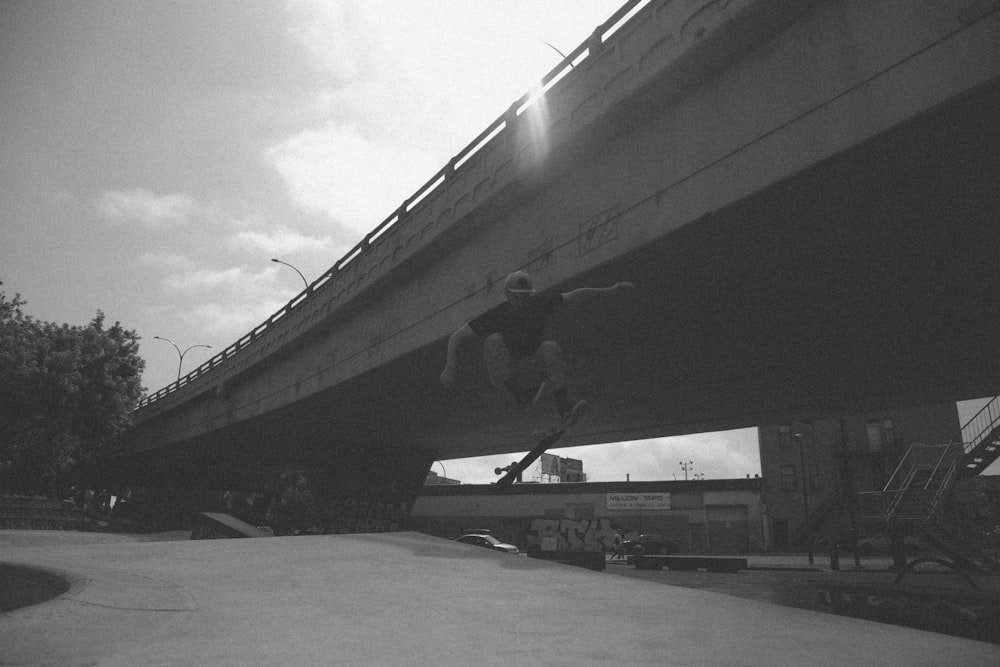 Graustufenfoto eines Mannes, der Tricks macht, während er Skateboard fährt