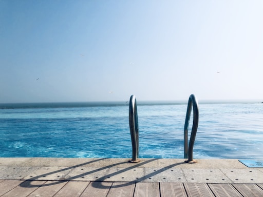 A friendly pool builder discussing plans with a happy family beside a sparkling in-ground steel wall pool.