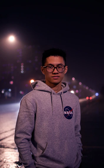 A close-up shot of a navycrew hoodie with bold amber orange stitching under city streetlights at dusk.