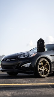 A sleek black car being carefully loaded onto a transport truck under a clear sky.