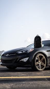 A sleek black car being carefully loaded onto a transport truck under a clear sky.