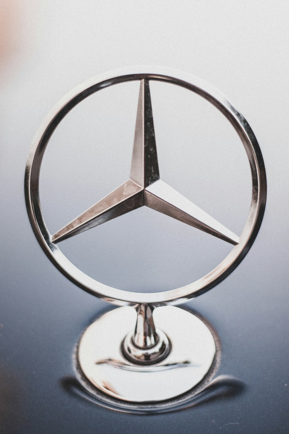 selective focus photography of Mercedes-Benz hood emblem
