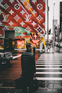 man holding black bags about to cross on the road