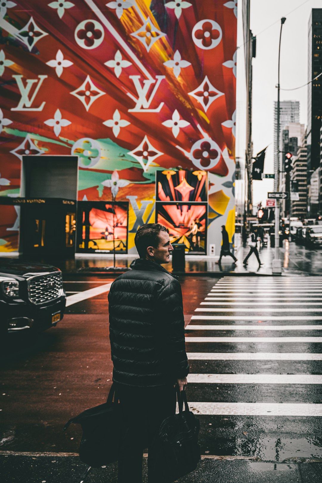 man holding black bags about to cross on the road