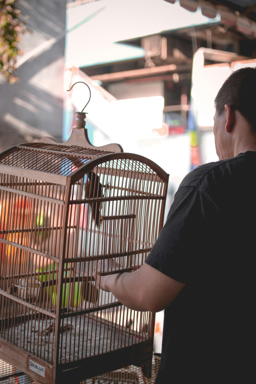 man standing in front of brown bird cage