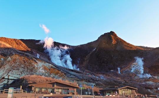 gray house under brown mountain during daytime in Owakudani Japan