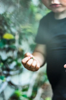 A child gently holding the Sensevoxx device outdoors surrounded by soft greenery.