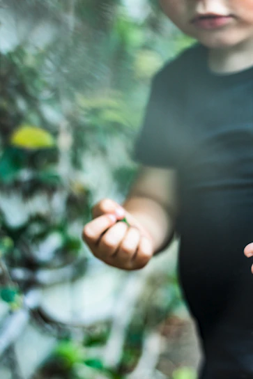 A child gently holding the Sensevoxx device outdoors surrounded by soft greenery.