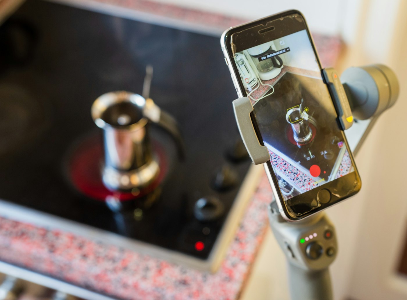 A phone mounted on a small stand filming a pot cooking on the stove, capturing the moment before a recipe gets saved