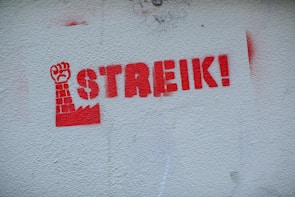 Graffiti on a brick wall depicting a raised fist symbolizing left-wing activism.