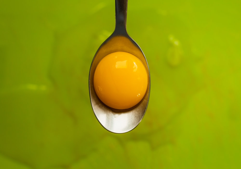 selective focus photography of eggyolk on gray spoon