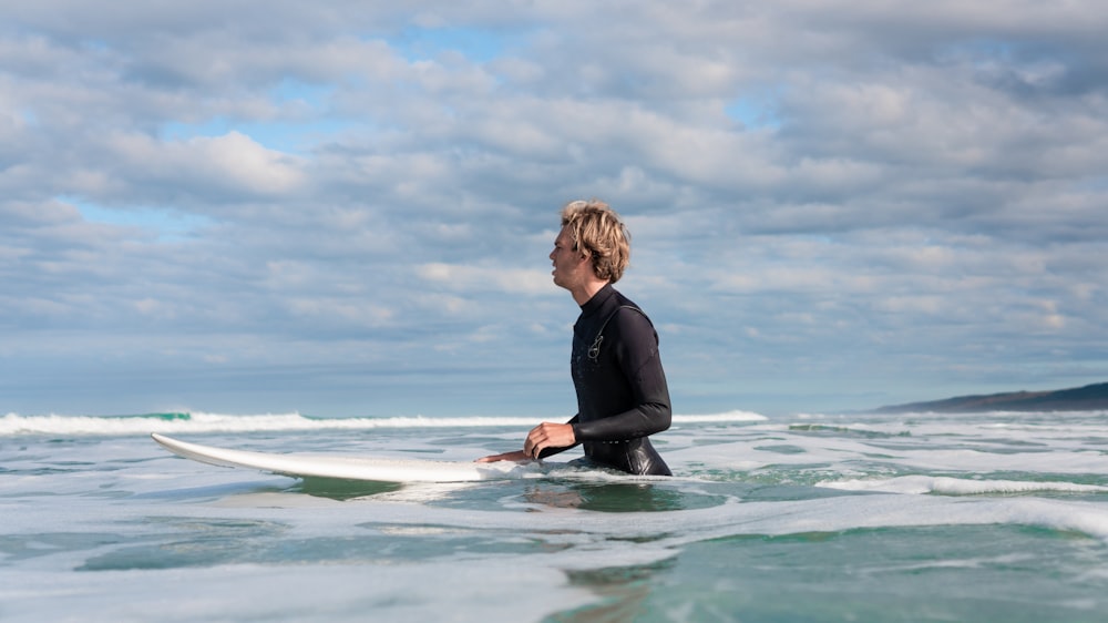 man soaked on water beside surfboard