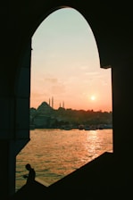 Majestic desert sunset with the silhouette of an Arabian arch framing a figure in regal Muslim attire.