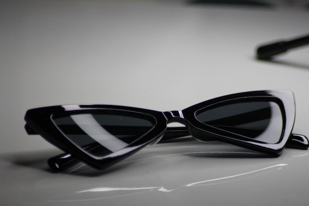 óculos de sol de armação preta na superfície branca