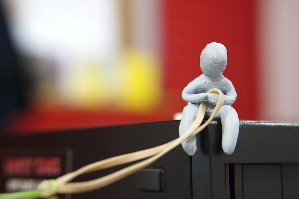 selective focus photography of sitting person holding strap figurine