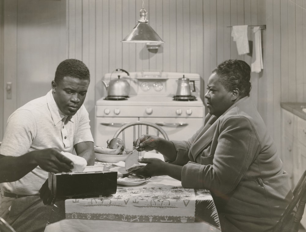 grayscale photography of man and woman sitting at a kitchen table in a scene from the film 'The Jackie Robinson Story'