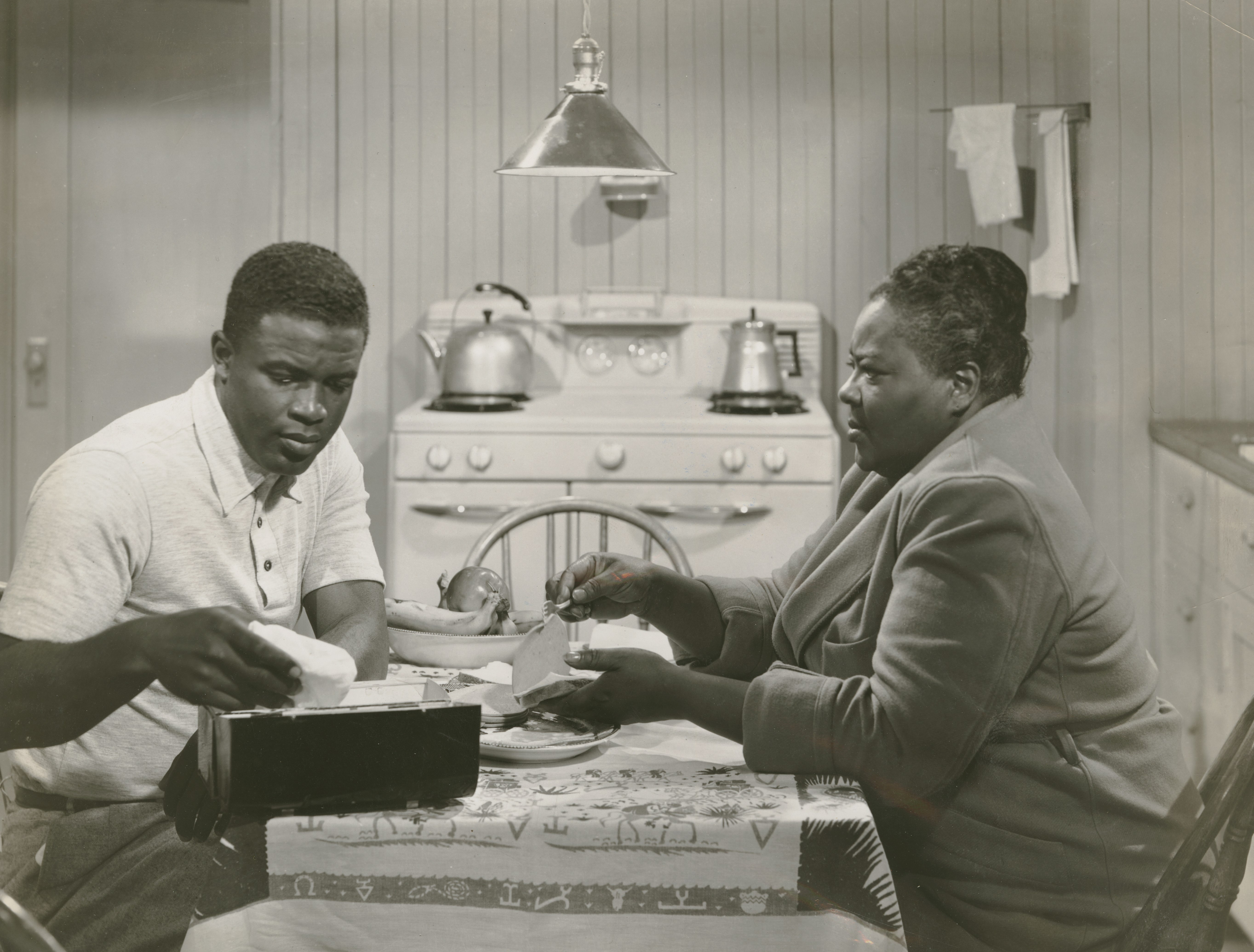 grayscale photography of man and woman sitting at a kitchen table in a scene from the film 'The Jackie Robinson Story'