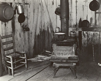 A rustic kitchen scene featuring a traditional wood-burning stove with cast iron pots simmering.
