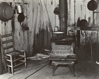 A rustic kitchen scene featuring a traditional wood-burning stove with cast iron pots simmering.