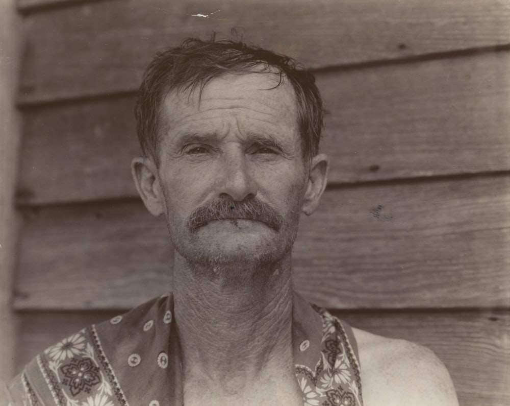 man with moustache standing near wall