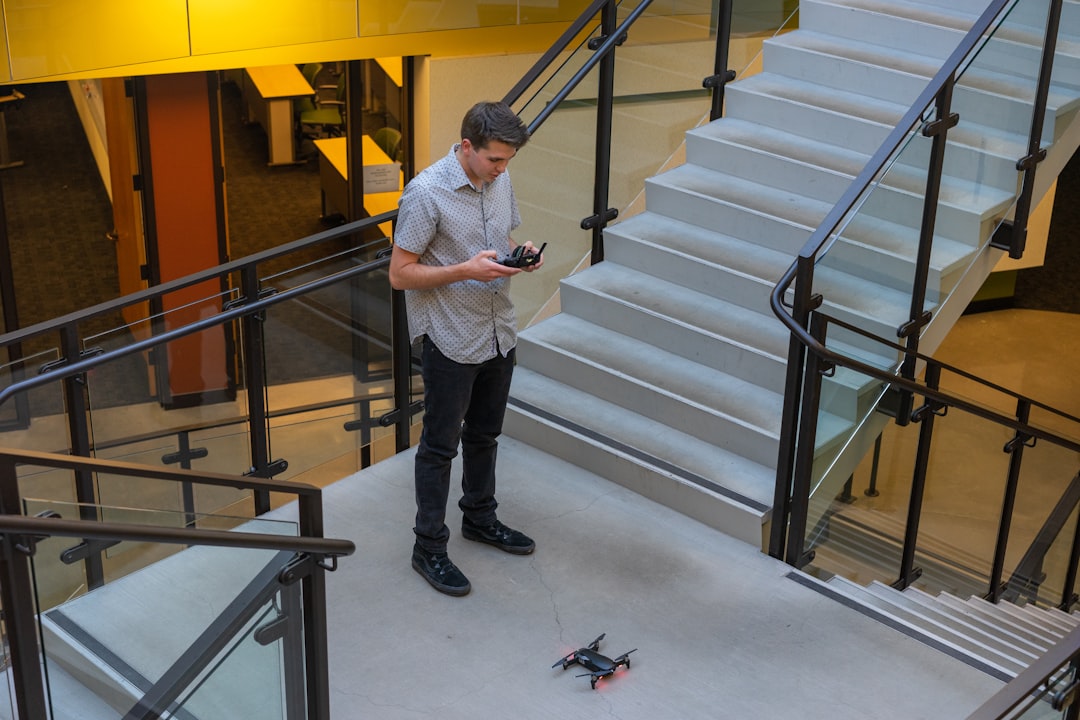 man controlling black quadcopter drone