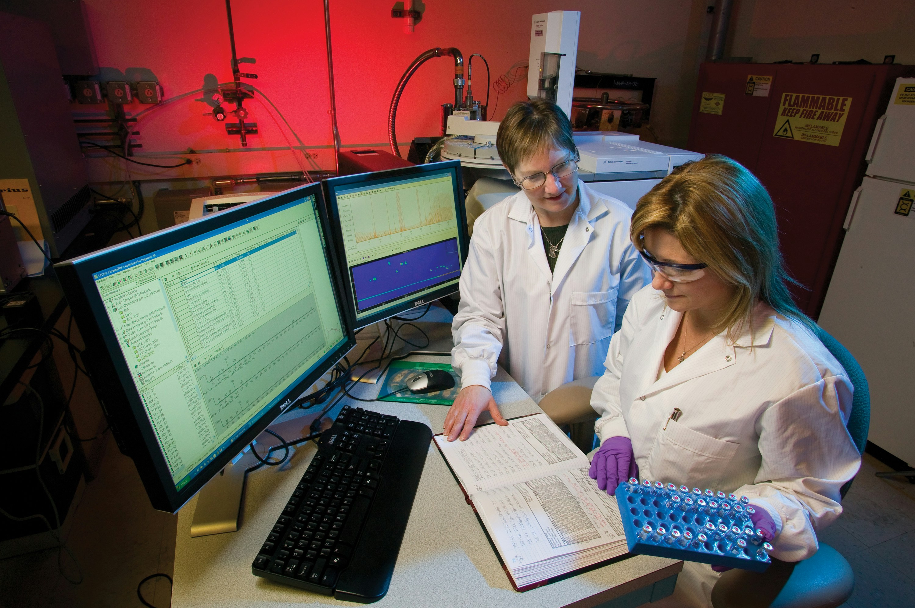 two women in white coat standing beside computer