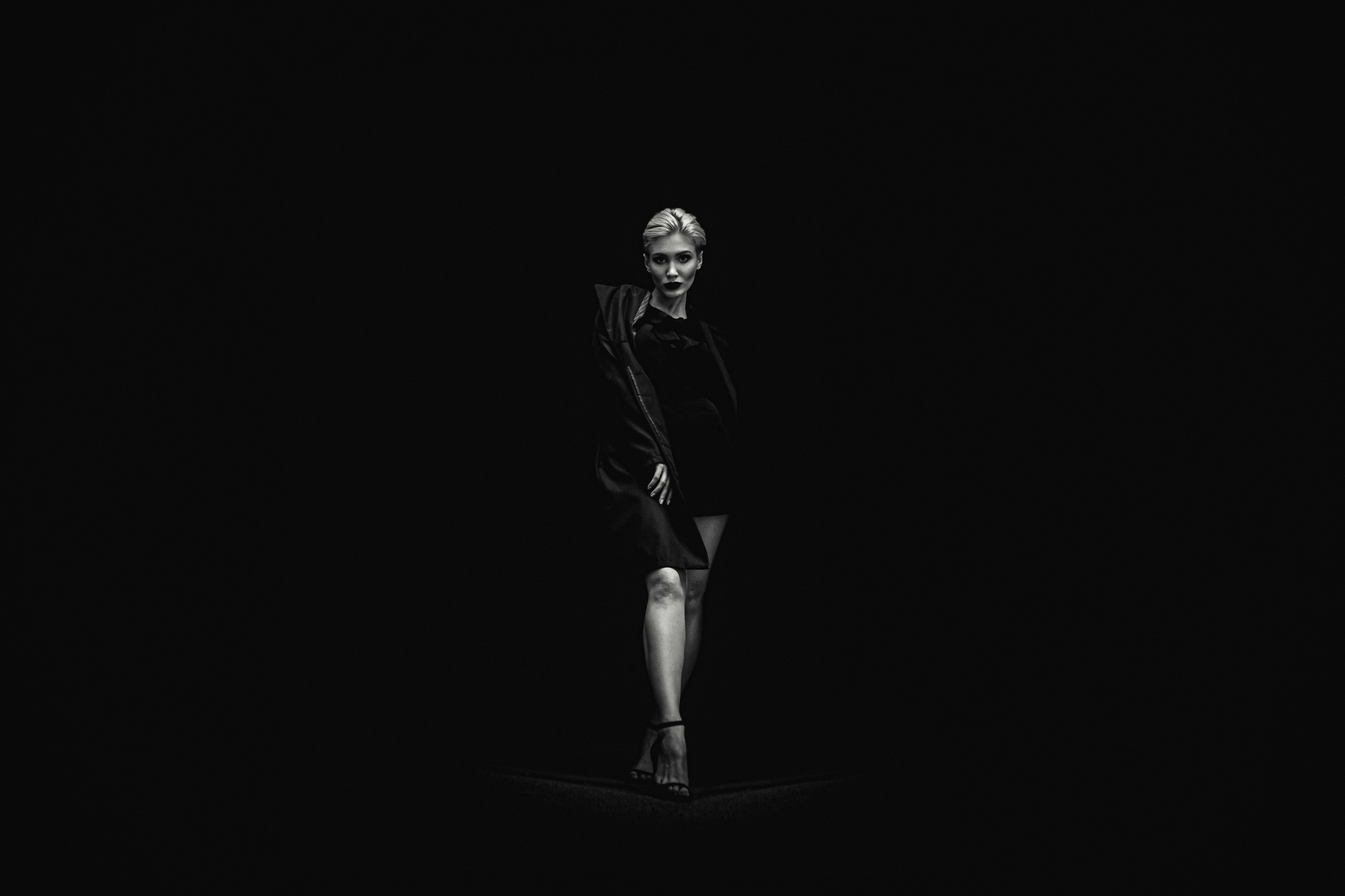 grayscale photo of standing woman near black surface