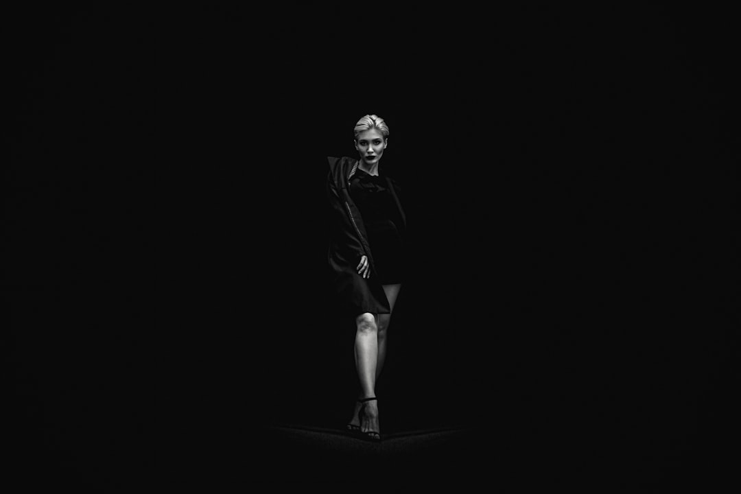 grayscale photo of standing woman near black surface